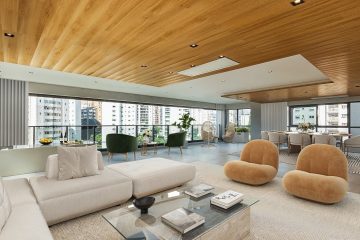 Sala de estar espaçosa em um imóvel de alto padrão, com móveis modernos, teto de madeira e ampla varanda com vista para a cidade. O ambiente integra conforto e sofisticação, ideal para viver.